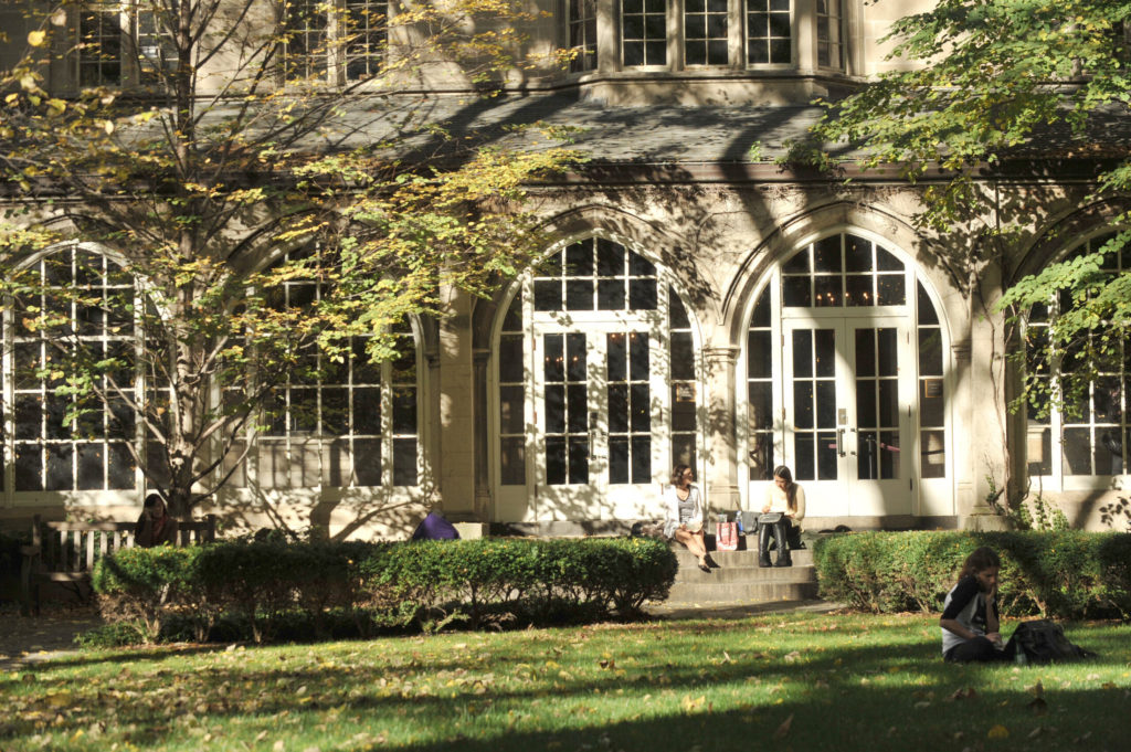 An image of the exterior of McCormick Hall at Northwestern Pritzker School of Law. Two female students sit on the front steps. 