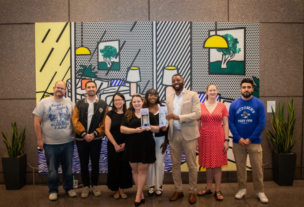 Members of the Northwestern Pritzker Law community in front of the painting "Wallpaper With Blue Interior" by Roy Lichtenstein. The painting is several feet wide and tall.