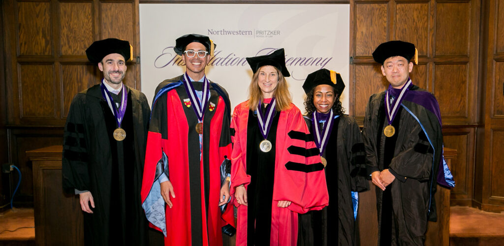 A photo of Interim Dean Zachary D. Clopton and Professors Paul Gowder, Jill Hortiz, Myriam Gilles, and Alex Lee in academic regalia